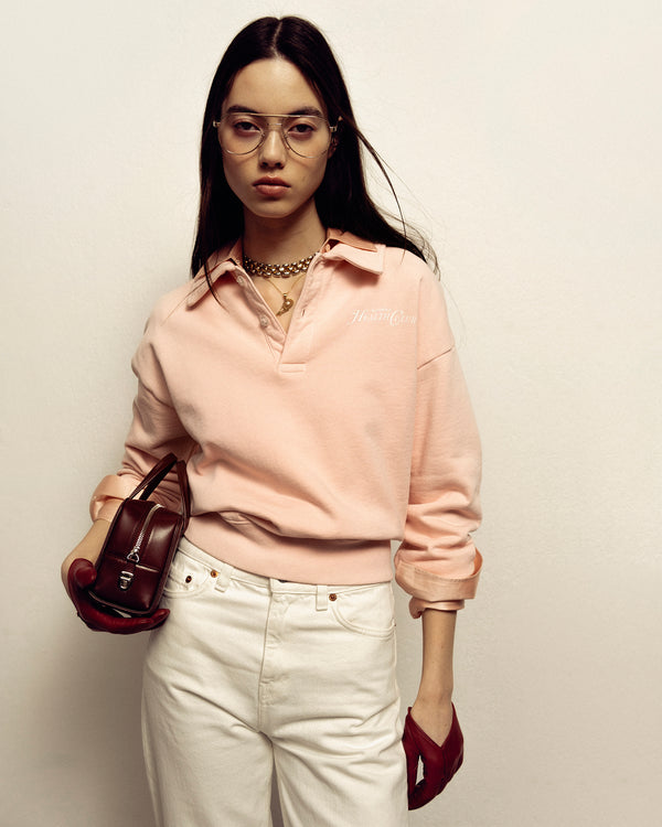 Woman in Rizzoli Polo - Ballet/White, white pants, holding a brown purse, wearing glasses and red gloves. Shrink free and made in Portugal.