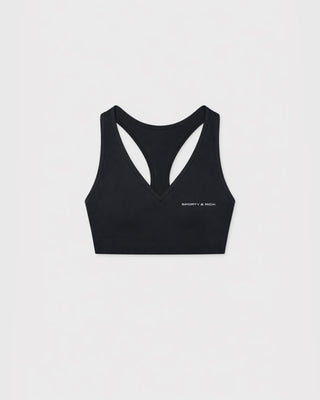 A black sports bra with a crossover V-neckline and double-strap back design, featuring the text 'SPORTY & RICH' printed in white on the lower left chest, displayed on a clean white background.