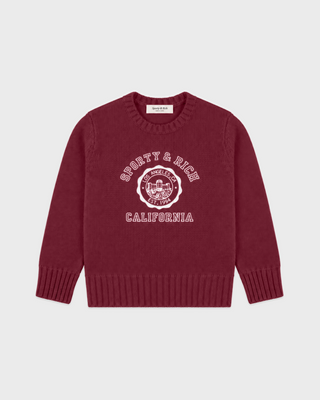 A merlot knit crewneck sweater with a white graphic print on the front reading 'SPORTY & RICH CALIFORNIA' around a crest emblem, shown flat against a light gray background.