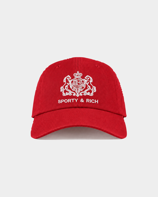 Maeve SR Hotel Hat – Ruby: This red baseball cap features a white embroidered crest and “SPORTY & RICH” text on the front, along with an adjustable back closure for a comfortable fit and vintage-inspired style.