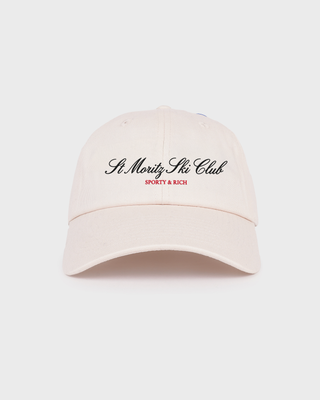 A light cream-colored baseball cap with 'St. Moritz Club' embroidered in black script and 'SPORTY & RICH' in red text on the front, set against a solid light gray background.