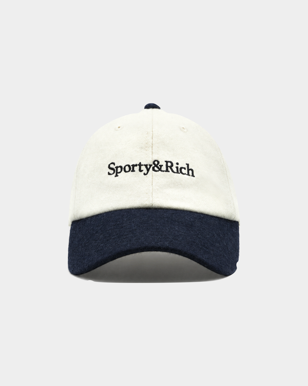 The Marcus Serif Logo Wool Hat in Off White/Dark Navy is a premium wool baseball cap designed for cold-weather comfort, featuring Sporty&Rich embroidery on the front and an adjustable back closure, displayed against a plain background.