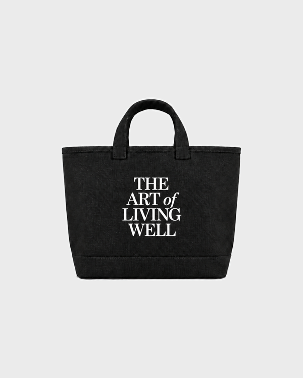 Maya Art OG Tote in black washed canvas, featuring the text THE ART of LIVING WELL printed on the front.