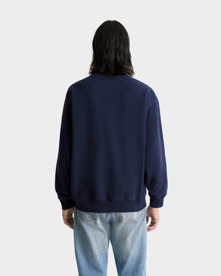 Person with long dark hair, seen from the back, wears the Vendome Embroidered Crewneck - Navy/White and light blue jeans.