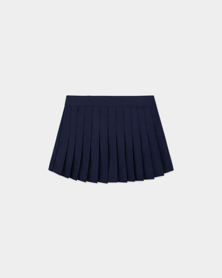 Person in a navy jacket, Abigail Signature Logo Abigail Skirt - Dark Navy, and cap stands against a plain white background.