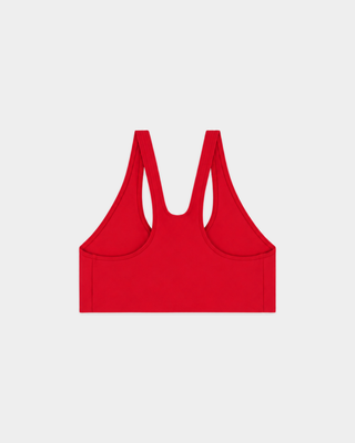 A woman in the Billie Signature Logo Sports Bra - Ruby stands against a plain white background, looking forward.