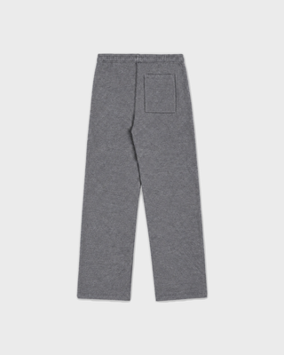 A person in an oversized LuxeFleece sweatshirt, Blakely Signature NY Wide Sweatpant, patterned beanie, and slippers.