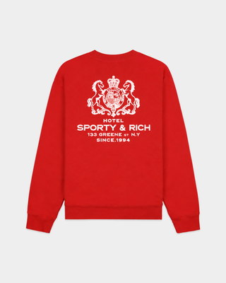 The Emmett Sr Hotel Crewneck - Ruby is a red crewneck sweatshirt inspired by vintage styles, featuring “Sporty & Rich” white logo and text on the left chest area.