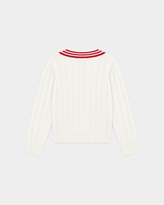 Person with braided hair wears the Item SRC Cricket Sweater in Off White/Ruby and blue jeans, facing away from the camera.