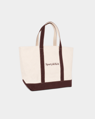 Mona Serif Logo Medium Tote in natural cotton with dark brown trim, handles, and a brown logo on the front.