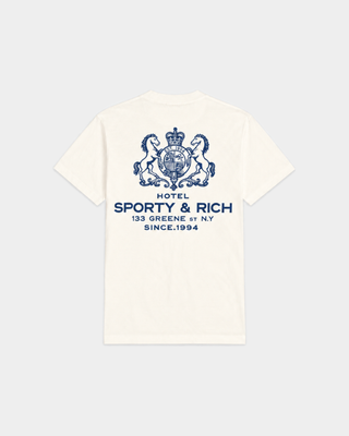 Cameron SR Hotel Tshirt - Off White features a blue crest and “Sporty & Rich Health Club” text on the left chest, crafted from 100% cotton for all-day comfort. This unisex T-shirt is a classic addition to any casual wardrobe.