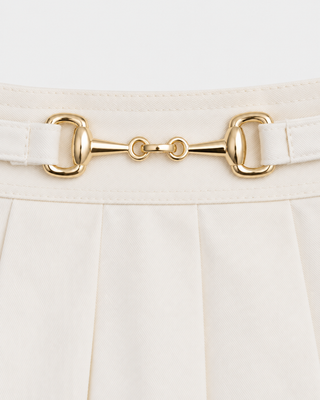Anais Riding Skirt in ecru, an off-white pleated equestrian skirt with gold-tone horsebit hardware at the waist.