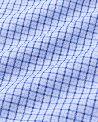 Coco SRC Oversized Shirt - Blue Mini Check features a blue and white mini check pattern in a long-sleeve, button-up, oversized silhouette with a collar. Crafted from breathable poplin for a relaxed fit, the shirt is displayed laid flat on a white background.