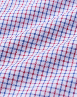 The Coco SRC Oversized Shirt - Blue White Red Check is a long-sleeve button-up featuring a small red, blue, and white checkered pattern, crafted from breathable poplin and displayed laid flat on a white surface.