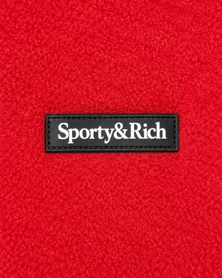 The Ezia Serif Logo Zipped Polar Fleece in Ruby/White features a bright red color with white trim, two front pockets, an adjustable hem for a perfect fit, and a small left chest logo—making it the ideal winter layer.