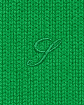 A close-up of bright green knitted fabric with a matching embroidered cursive letter 'S' centered on it.