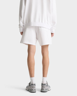 Person facing away, wearing a white sweatshirt, Made In USA Gym Short - White/Navy/Fire Red with drawstring waistband, white socks, and gray sneakers.
