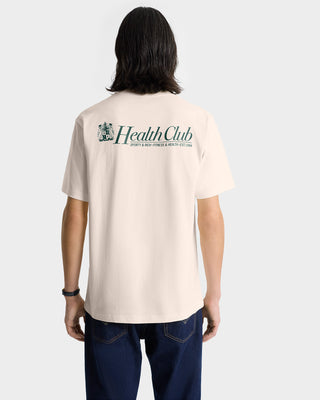 Person in a Lion Health T-Shirt - Cream/Navy, featuring Health Club text on the back, made in Portugal from 100% cotton, standing with their back facing the camera.