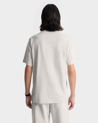Person with shoulder-length hair wearing the NY Health Club T-Shirt in heather gray/navy and pants, shown from the back. The t-shirt is made from 100% cotton for comfort and durability.