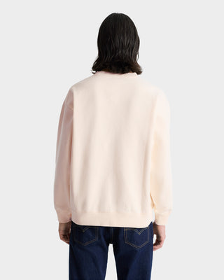 Person with shoulder-length dark hair, facing away from the camera, wearing the Wellness Club Embroidered Crewneck in cream/navy and dark jeans.