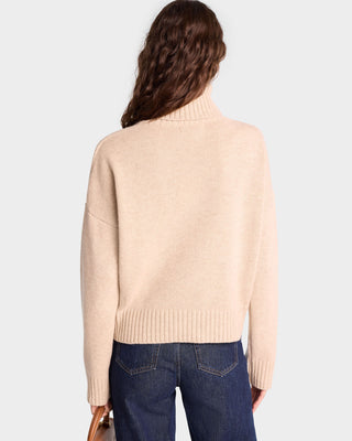 A woman with wavy brown hair, shown from the back, wears an oversized fit SRC Wool Turtleneck in Cream/White and blue jeans.