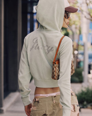 Person wearing a light green hoodie with 'Gucci' branding, standing outdoors.