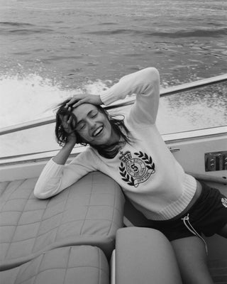 Person on a boat wearing a sweater with a logo, black and white photo