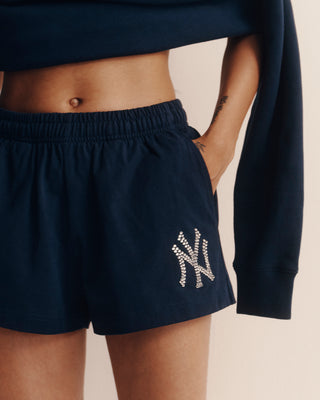Navy blue shorts with a logo worn by a person on a beige background