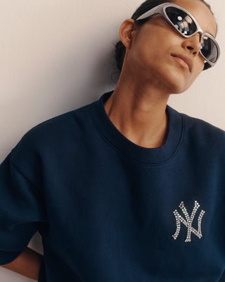 Person wearing a navy blue sweatshirt with a logo, posing against a plain background