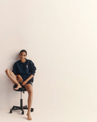 Person sitting on a black office chair against a plain background