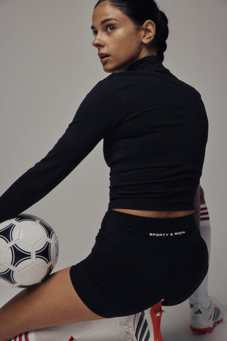 Freya Bold Logo Sports Jacket - Black: A black zip-up, long-sleeve cropped performance jacket crafted from technical stretch fabric, featuring “SACONY & RICH” text on the left chest, shown on a white background.