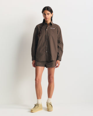 Cora Signature Logo BD Shirt in chocolate garment-dyed cotton with white cursive logo embroidery on the chest.