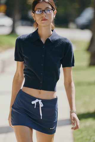 Jannie Signature Logo Cashmere SS Cardigan in Dark Navy—this cropped, short-sleeve knit features a button front, classic collar, and subtle signature embroidery on the left chest for a modern touch.