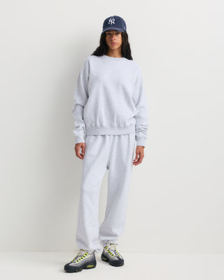 The Eeva Serif Logo Embroidered Crewneck in Heather Gray features a classic crewneck design with long sleeves and subtle white embroidered text on the left chest, making it perfect for fans of vintage-style sweatshirts.
