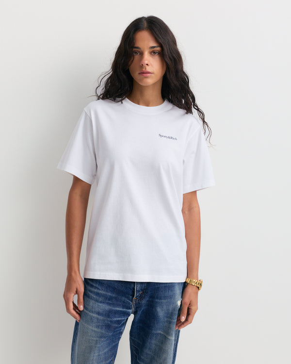 Fema Serif Logo Tshirt - White: a unisex T-shirt crafted from 100% cotton, showcasing the Sporty & Rich logo in small black serif text on the left chest, set against a plain background.