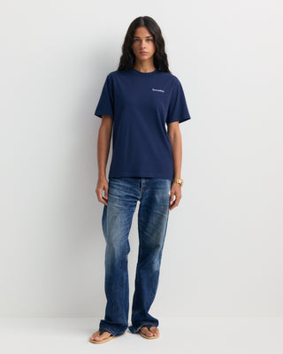 The Fema Serif Logo T-shirt in Dark Navy features a short-sleeve, unisex design with text on the left chest, crafted from 100% cotton and shown laid flat on a white background. This Sporty & Rich tee offers both comfort and timeless style for any wardrobe.