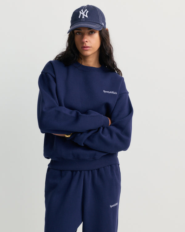 Dark navy Eeva Serif Logo Embroidered Crewneck featuring embroidered text on the upper left chest, laid flat on a white background.