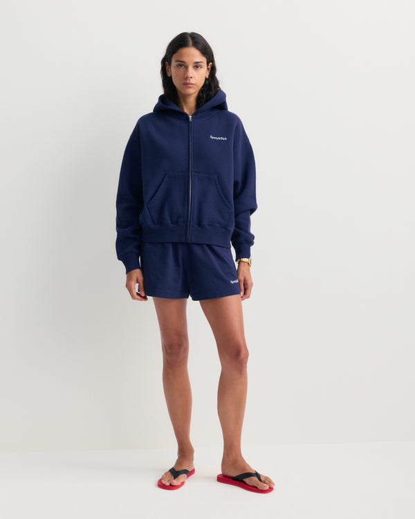 The Lucy Serif Logo Embroidered Disco Short in Dark Navy features an elastic waistband and Sporty & Rich text embroidered on the front left side, making these cotton lounge shorts perfect for a relaxed yet sporty look.