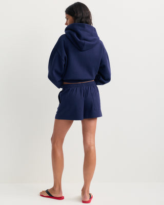 The Lucy Serif Logo Embroidered Disco Short in Dark Navy features an elastic waistband and Sporty & Rich text embroidered on the front left side, making these cotton lounge shorts perfect for a relaxed yet sporty look.