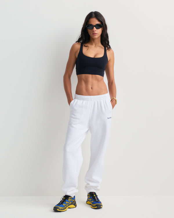 The Brianno Serif Logo Embroidered Jogger in White features elastic cuffs and waistband, front pockets, and a small embroidered Sporty & Rich logo on the left hip, offering a classic jogger fit inspired by their iconic sweatpants.