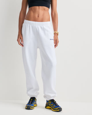 The Brianno Serif Logo Embroidered Jogger in White features elastic cuffs and waistband, front pockets, and a small embroidered Sporty & Rich logo on the left hip, offering a classic jogger fit inspired by their iconic sweatpants.
