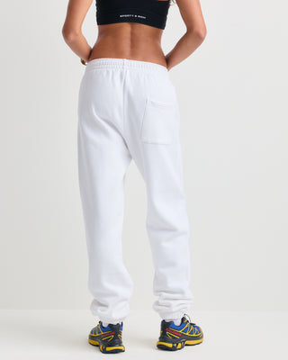 The Brianno Serif Logo Embroidered Jogger in White features elastic cuffs and waistband, front pockets, and a small embroidered Sporty & Rich logo on the left hip, offering a classic jogger fit inspired by their iconic sweatpants.