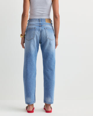 The Straight Jean - Light Wash is a pair of light blue, high-rise denim jeans featuring five pockets and a slightly faded finish. Expertly crafted in Italy, these jeans are laid flat to showcase their classic straight-leg silhouette.