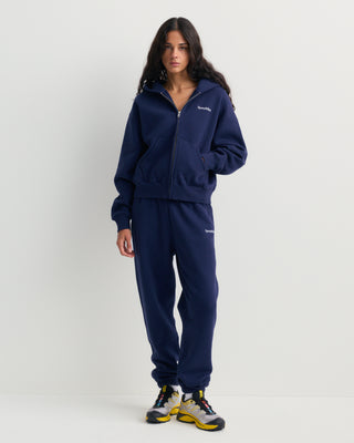 Emaro Serif Logo Embroidered Zip Hoodie in Dark Navy, laid flat. This relaxed fit hoodie features front pockets, an embroidered Sporty & Rich logo on the left chest, and an ultra-soft feel for everyday comfort.