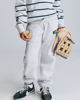 Kais Wellness Ivy Kids Jogger in heather gray with WELLNESS printed in dark blue on the left hip.
