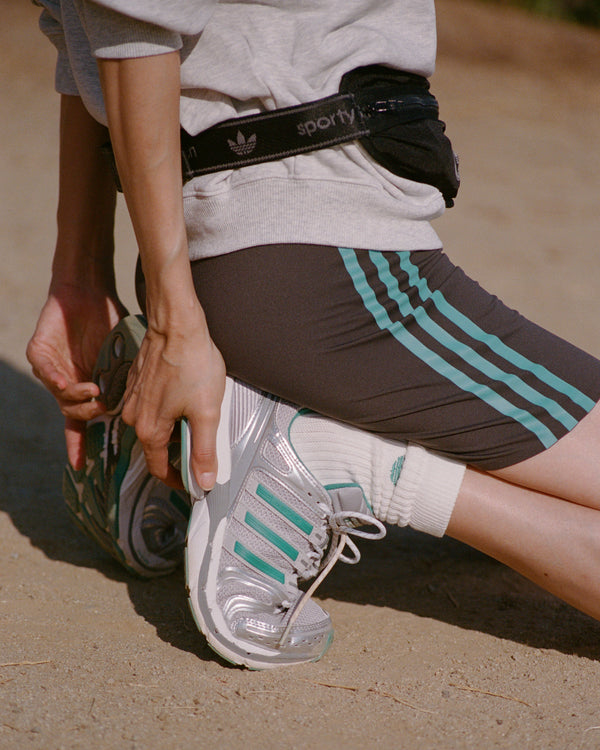 Person wearing Adidas shoes and shorts on a sandy surface