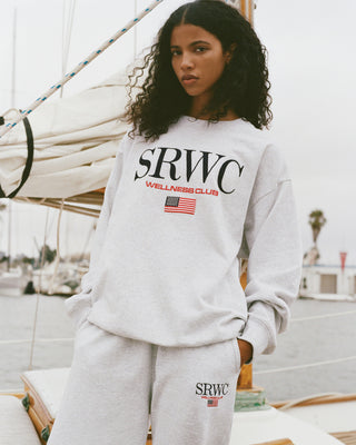 Person wearing a gray sweatshirt with 'SRWC Wellness Club' text on a boat