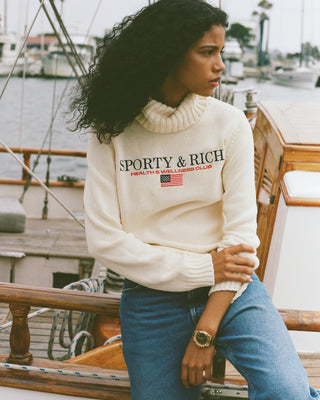 Person wearing a Sporty & Rich sweater on a boat