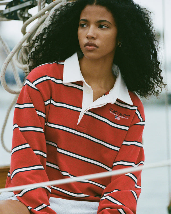 Woman wearing a red and white striped shirt with a brand logo, sitting on a boat.
