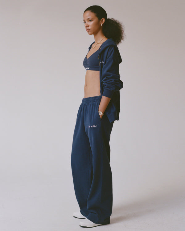 Person wearing a navy blue tracksuit on a plain background